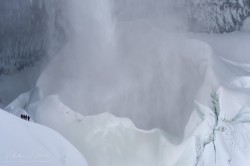 Ice climbers on the edge of a frozen ice cone of Helmcken Falls.