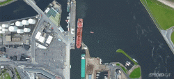 Incredible overhead view of an oil tanker perfectly docking at a narrow port