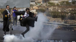 Palestinian lawyer, in full garb, kicks a tear gas canister back at the IDF