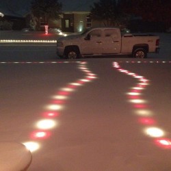 Christmas lights still glowing beneath the snow