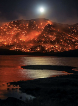 Moon rising over burning California hills, in Lake Isabella