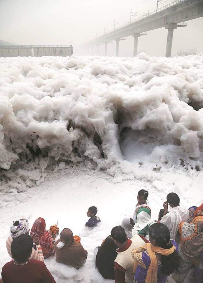 People offering prayers at the Yamuna River, India, which is frothing from industrial waste