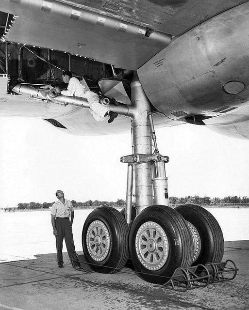 A mechanic hangs off the main landing gear strut of a B-36 Peacemaker. The payload for this airc ...